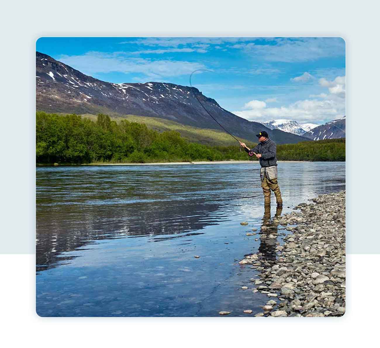 man fishing by mountains